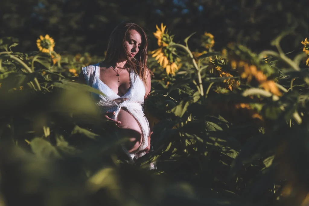 Femme enceinte debout dans un champ de tournesols,