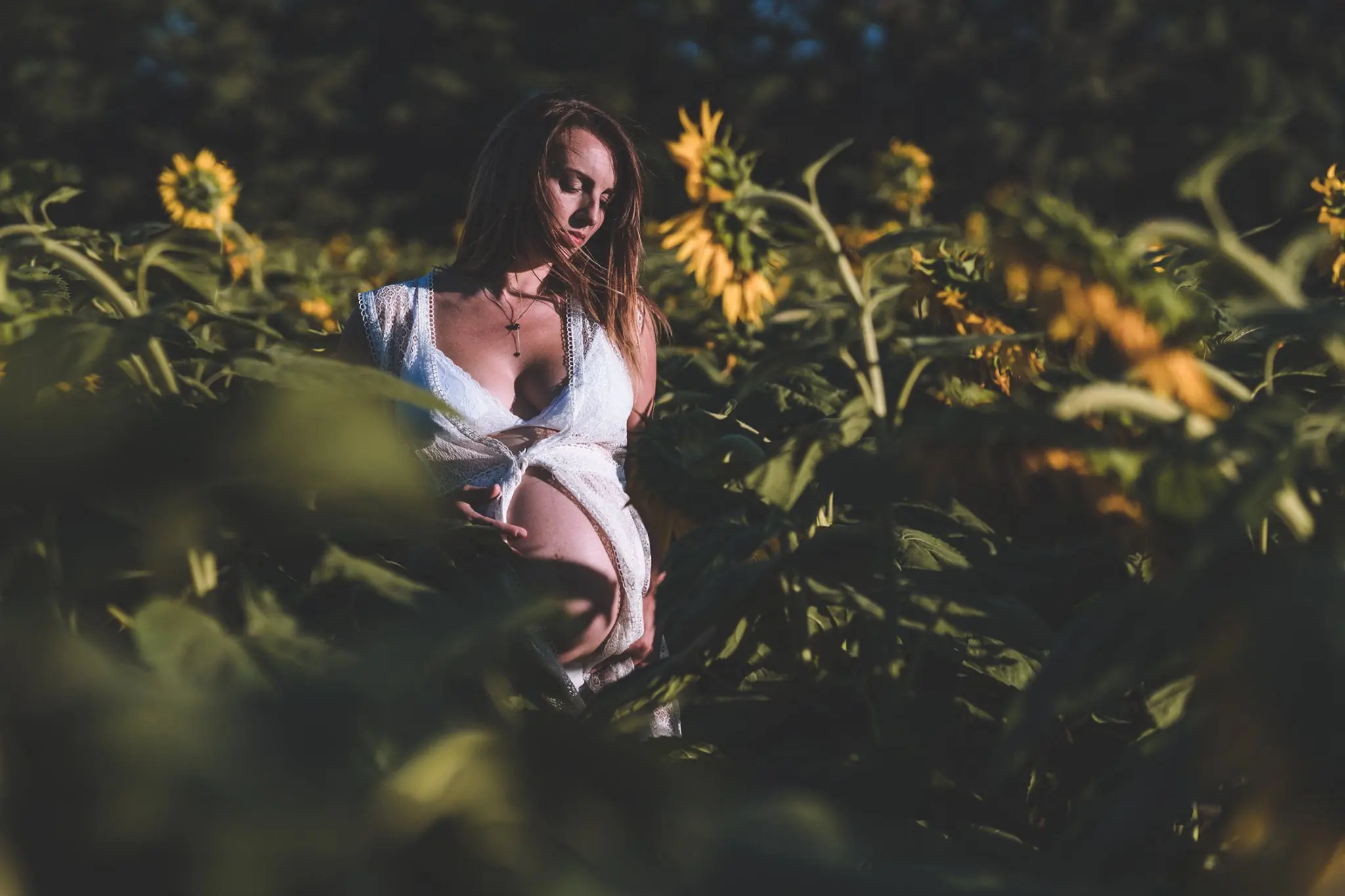 Femme enceinte debout dans un champ de tournesols,
