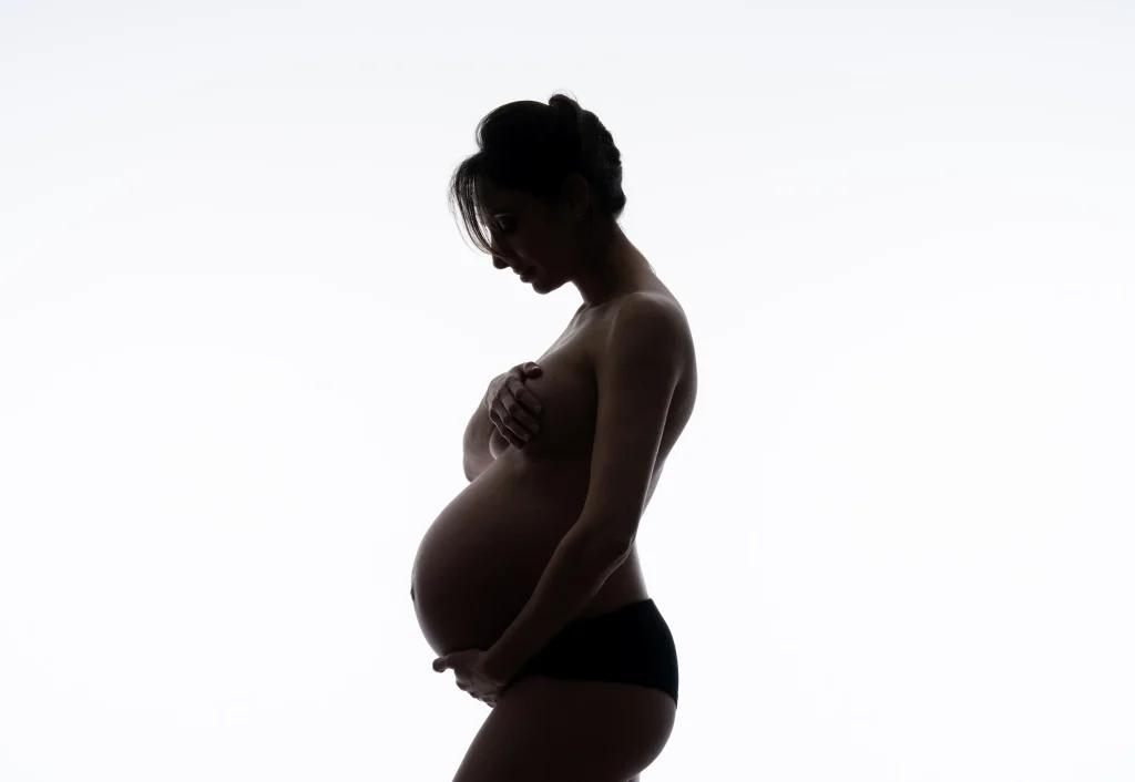 Profil d’une femme enceinte portant uniquement un sous-vêtement noir,