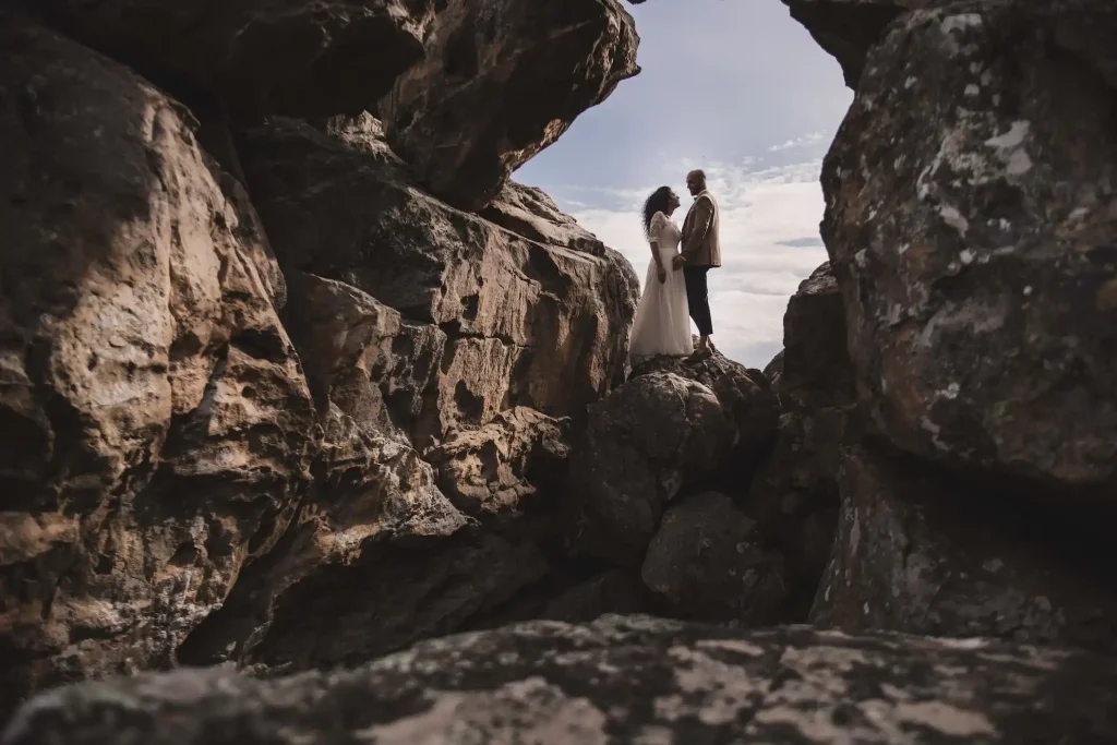 Couple de mariés debout sur des rochers dans une formation rocheuse naturelle ou grotte