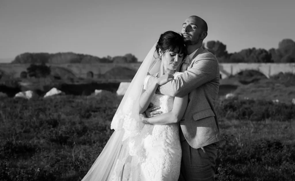 Couple de mariés enlacé tendrement dans un champ, photo en noir et blanc