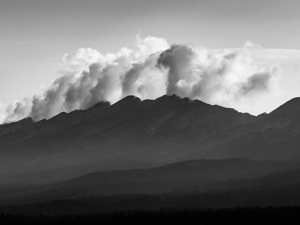 Paysage montagneux dramatique en noir et blanc avec des nuages orageux s'accumulant au-dessus des crêtes